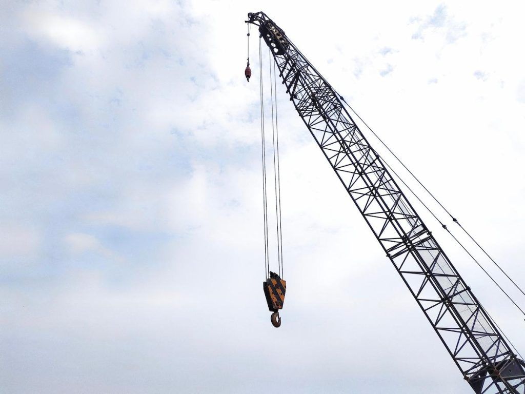 A boom or lattice boom and hook on a crawler crane, also known as a lattice boom crane.