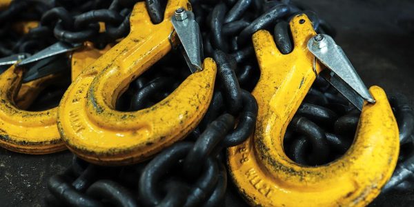 Iron chains with hooks lie on the floor of the workshop.