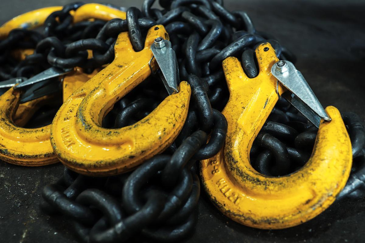 Iron chains with hooks lie on the floor of the workshop.